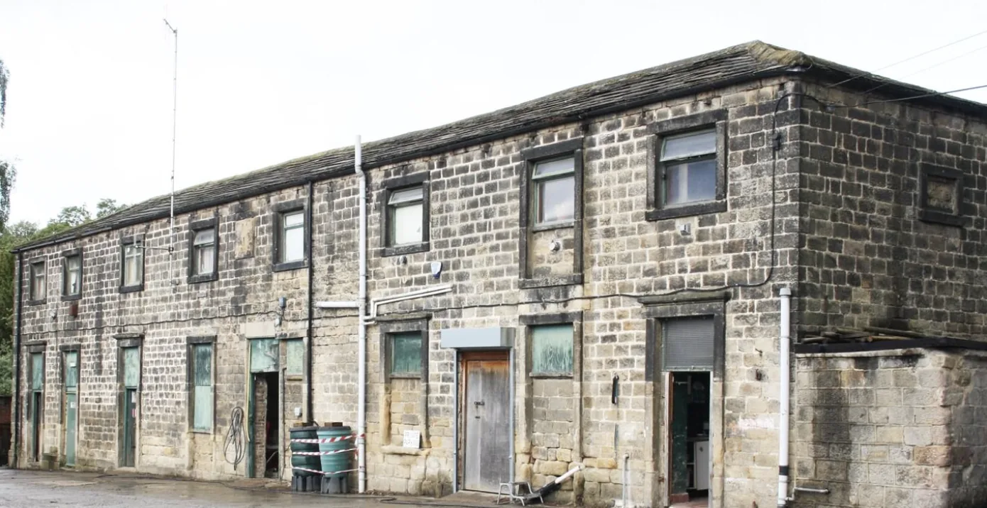 The two-storey stables building with boarded green doors and stone mullioned windows
